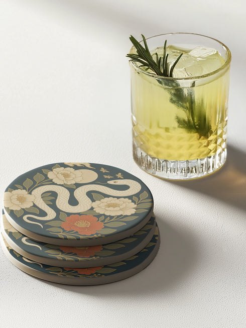 Round ceramic coaster with a chinoiserie-inspired design featuring a white snake among golden peonies, butterflies, and a glowing moon on a dark green background. Surrounded by floral and botanical accents with a soft vintage aesthetic. The coaster has a cork back and measures about 4 inches in diameter. Ideal for mugs, teacups, or wine glasses, this decorative piece suits witchy, victorian, and chinoiserie-inspired decor.
